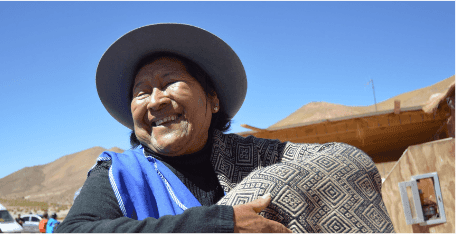 A woman smiling and showing off a woven blanket